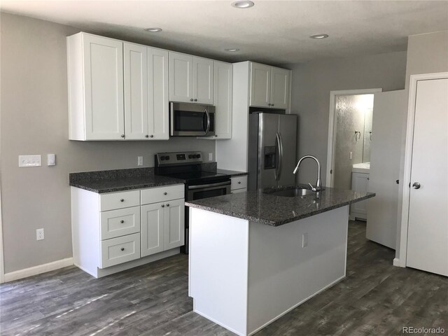 kitchen with white cabinets, stainless steel appliances, washer / clothes dryer, and a center island with sink