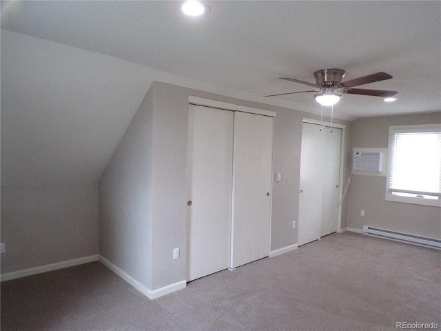 interior space with ceiling fan, a baseboard heating unit, an AC wall unit, light colored carpet, and vaulted ceiling