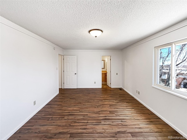 unfurnished bedroom with dark wood-style floors, ensuite bath, a textured ceiling, and baseboards