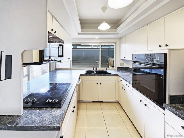 kitchen featuring dark countertops, a tray ceiling, crown molding, black appliances, and a sink