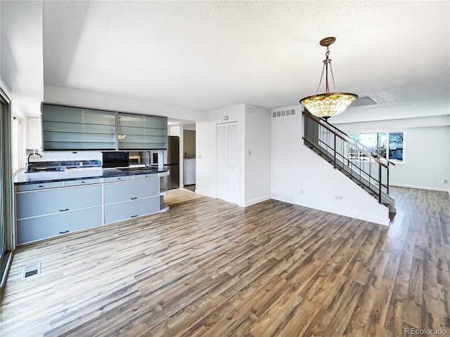 kitchen featuring a textured ceiling, wood finished floors, dark countertops, and a sink