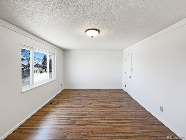 spare room featuring a textured ceiling, wood finished floors, visible vents, and baseboards