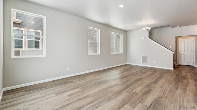 empty room featuring a chandelier and light hardwood / wood-style flooring