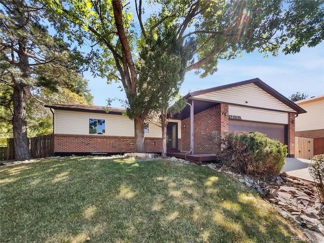 ranch-style home with brick siding, an attached garage, a front lawn, and fence