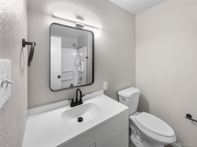 bathroom with vanity, toilet, and a textured wall