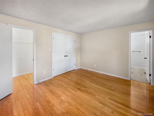 unfurnished bedroom with light wood-type flooring, baseboards, and a textured ceiling