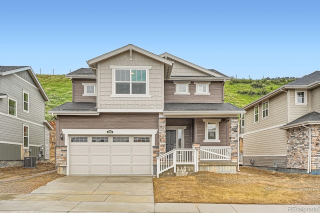 7357 S Yank Ct, Littleton, CO 80127 - craftsman inspired home featuring an attached garage, driveway, a porch, central AC unit, and stone siding