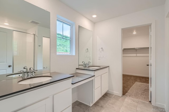 7357 S Yank Ct, Littleton, CO 80127 - bathroom featuring a tile shower, two vanities, a spacious closet, and recessed lighting