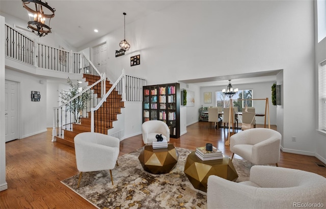 living area featuring a high ceiling, a notable chandelier, wood finished floors, and stairway