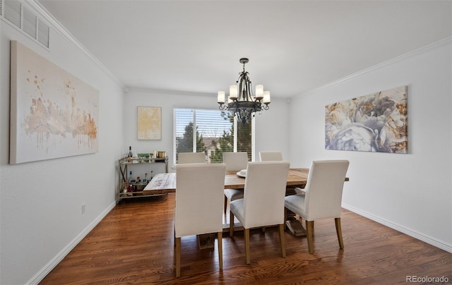 dining room featuring crown molding, a notable chandelier, visible vents, and dark wood finished floors