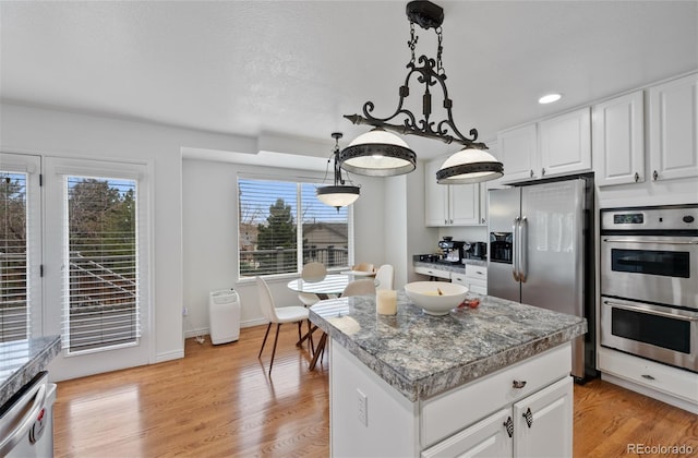 kitchen featuring pendant lighting, appliances with stainless steel finishes, a center island, and white cabinetry
