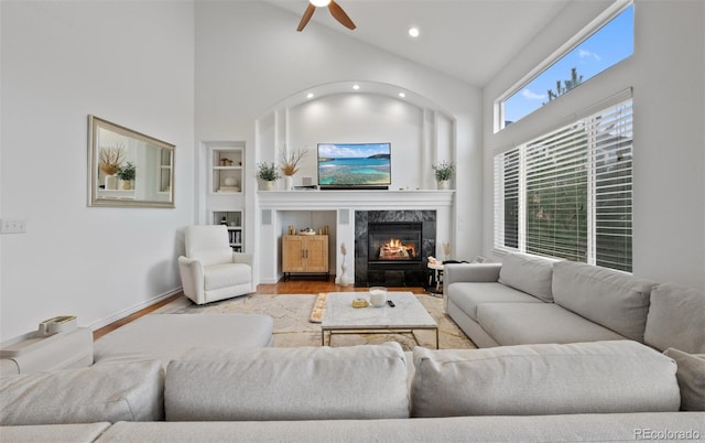 living room with ceiling fan, built in shelves, recessed lighting, wood finished floors, and a high end fireplace