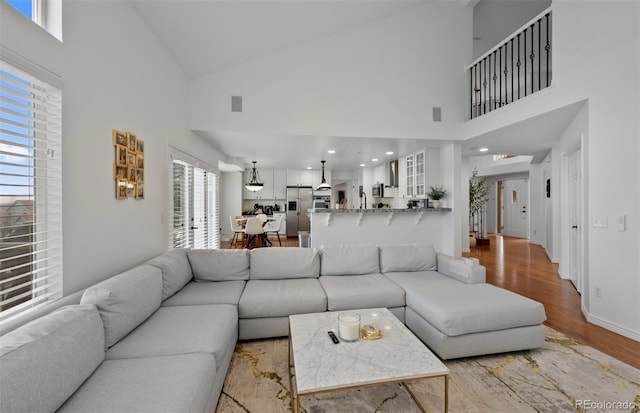 living room with high vaulted ceiling, baseboards, and wood finished floors