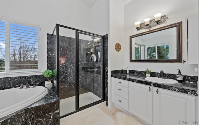 bathroom with a healthy amount of sunlight, a marble finish shower, and vanity