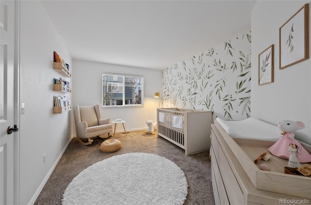 bedroom with wallpapered walls, a crib, baseboards, and carpet