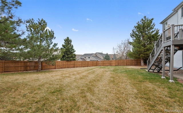view of yard with a fenced backyard and stairs