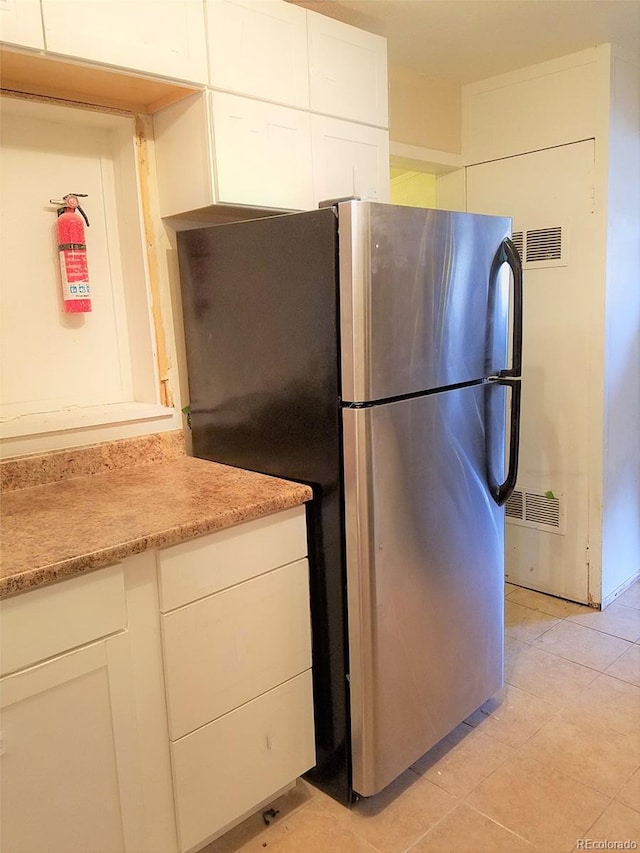 kitchen featuring stainless steel refrigerator, white cabinetry, and light tile patterned floors