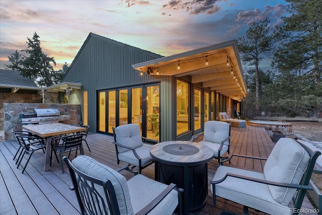 deck at dusk with outdoor dining area and a grill