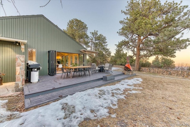 deck at dusk featuring outdoor dining space and area for grilling