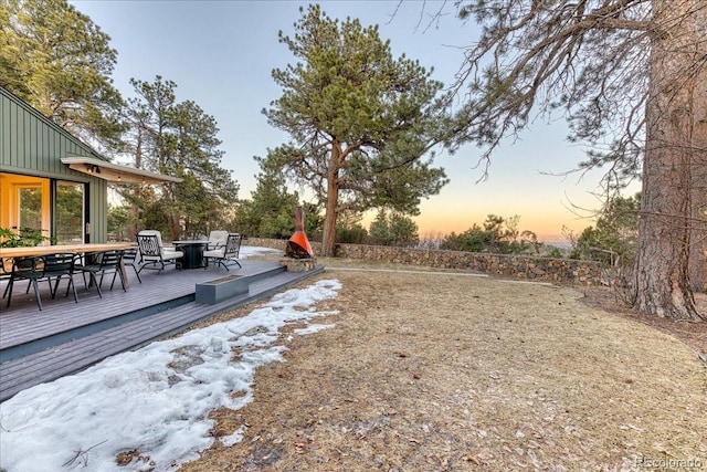 yard at dusk featuring outdoor dining area and a deck