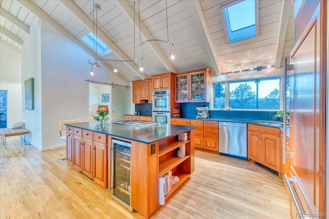 kitchen featuring a skylight, dark countertops, beamed ceiling, stainless steel appliances, and open shelves