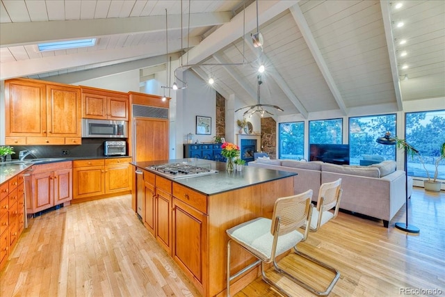 kitchen with light wood-style floors, a fireplace, a kitchen island, and stainless steel appliances