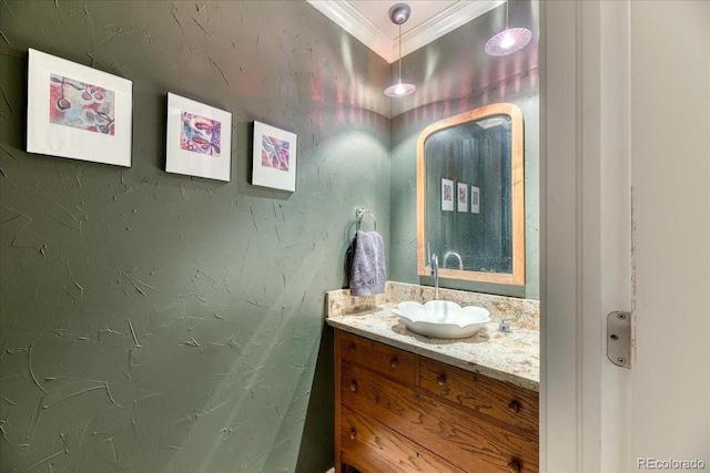 bathroom with a textured wall, ornamental molding, and vanity