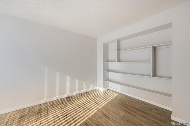 empty room with dark hardwood / wood-style floors and a textured ceiling