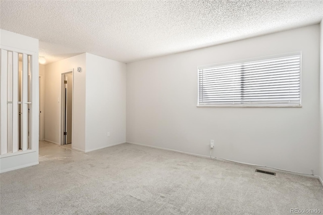 spare room with light carpet and a textured ceiling