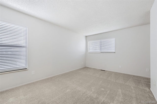 carpeted empty room with a textured ceiling