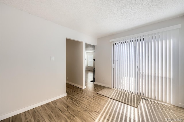 spare room with wood-type flooring, a textured ceiling, and plenty of natural light