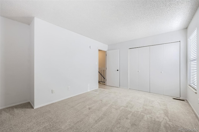 unfurnished bedroom with light carpet and a textured ceiling