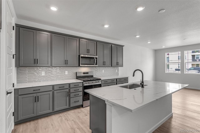 1415 Great Western Dr, Longmont, CO 80501 - kitchen featuring stainless steel appliances, a sink, light wood finished floors, tasteful backsplash, and recessed lighting
