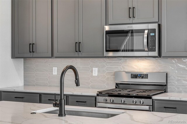 1415 Great Western Dr, Longmont, CO 80501 - kitchen with stainless steel appliances, gray cabinets, tasteful backsplash, a sink, and light stone countertops