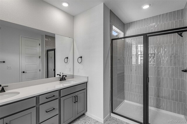 1415 Great Western Dr, Longmont, CO 80501 - bathroom featuring a shower stall, baseboards, double vanity, speckled floor, and recessed lighting