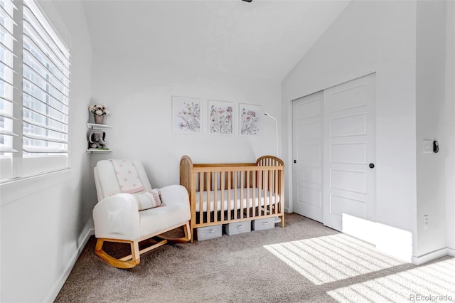 carpeted bedroom with a nursery area, lofted ceiling, and a closet