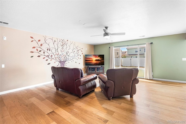 living room with light wood-style flooring, ceiling fan, and baseboards