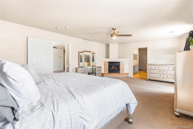 carpeted bedroom featuring a tiled fireplace and a ceiling fan