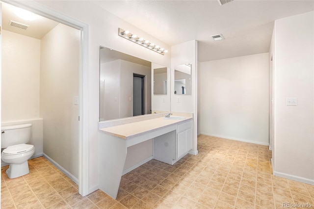 bathroom with toilet, vanity, and baseboards