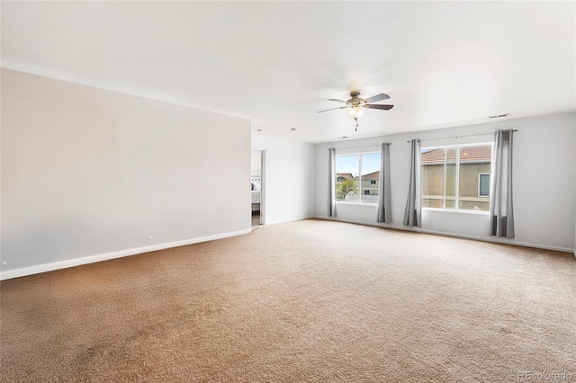 carpeted empty room featuring ceiling fan and baseboards