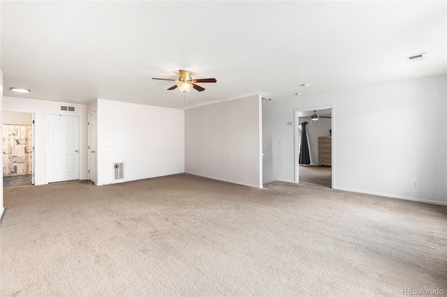 carpeted spare room with a ceiling fan and baseboards