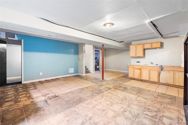 finished basement featuring a sink, baseboards, stairway, and a textured ceiling