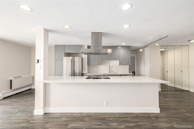 kitchen featuring freestanding refrigerator, island exhaust hood, gray cabinets, a sink, and light countertops