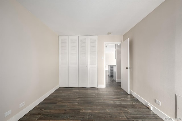 unfurnished bedroom with baseboards, dark wood-style floors, and a closet
