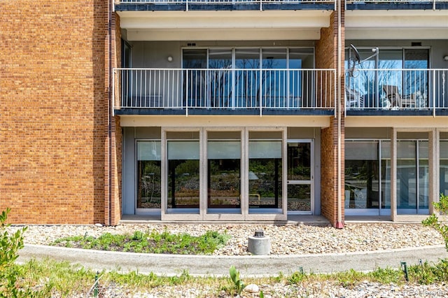 rear view of property with brick siding and a balcony