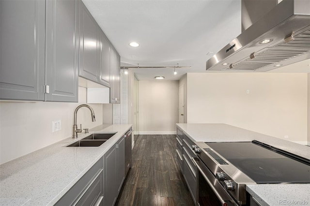 kitchen with wall chimney exhaust hood, a sink, appliances with stainless steel finishes, gray cabinets, and dark wood finished floors
