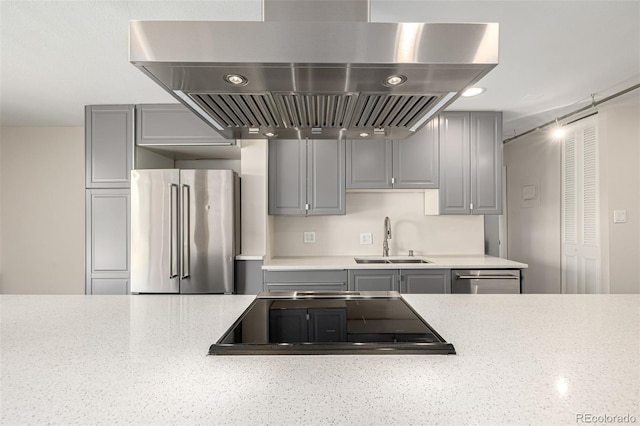 kitchen featuring stainless steel appliances, island exhaust hood, a sink, and gray cabinets