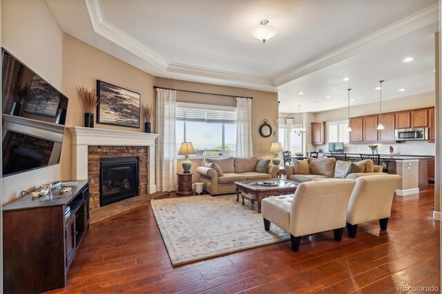 living room featuring a fireplace, plenty of natural light, a raised ceiling, and dark hardwood / wood-style flooring