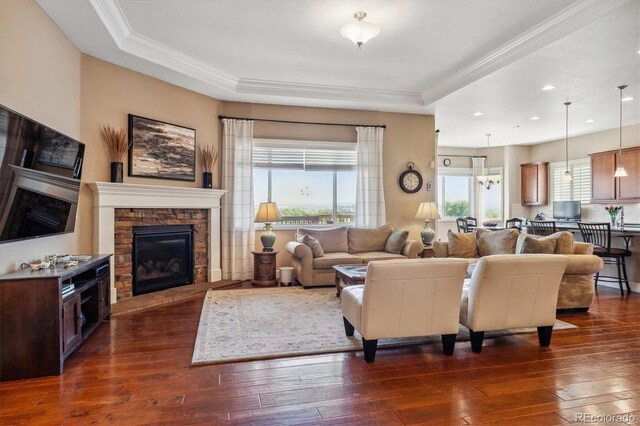 living room featuring crown molding, a stone fireplace, a raised ceiling, and dark hardwood / wood-style flooring