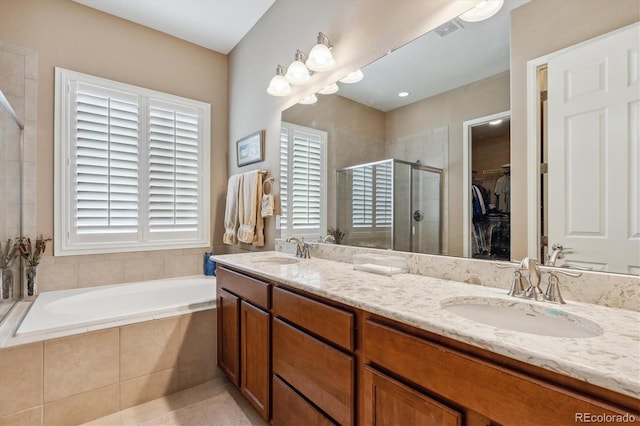 full bath with double vanity, a stall shower, a spacious closet, and a sink